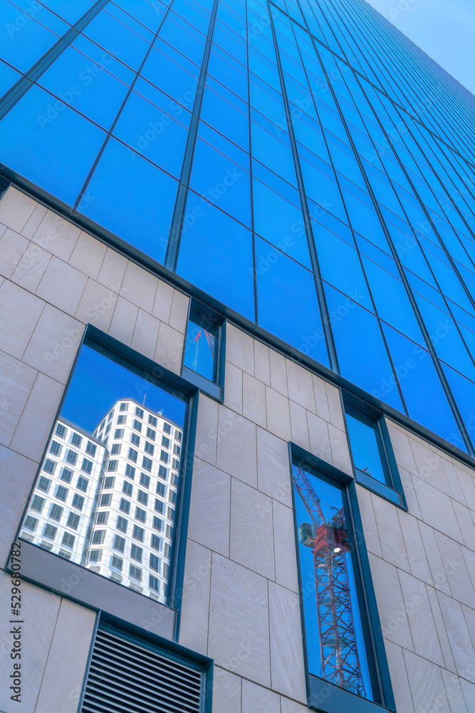 Obraz premium Modern building exterior with glass facade reflecting a construction crane