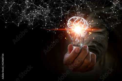 Hand of a man holding lightbulb with glowing virtual brain and connection line to creative thinking for innovation network and inspiration future imagination concept.