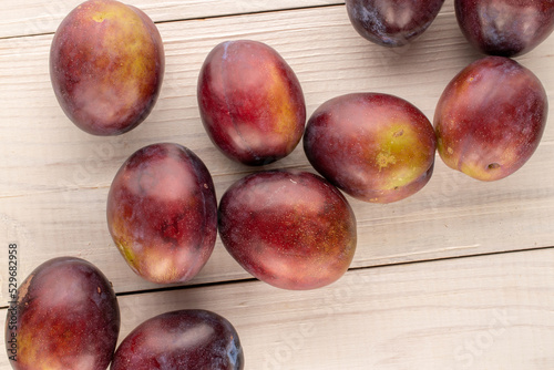 Several sweet plums on a wooden table, close-up, top view.
