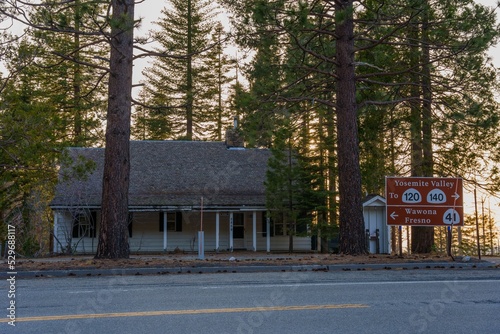 Cabin house by the road next to signage showing the directions to Yosemite Valley and Wawona photo