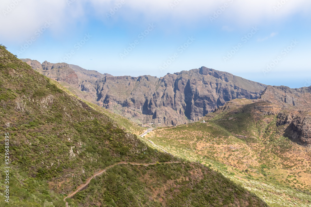 Panoramic view on scenic hiking trail over lush green hill in Teno mountain range, Tenerife, Canary Islands, Spain, Europe. Path leads to remote village Masca. Moody mystical vibes on tropical island Panoramic view on scenic hiking trail over lush green hill in Teno mountain range, Tenerife, Canary Islands, Spain, Europe. Path leads to remote village Masca. Moody mystical vibes on tropical island