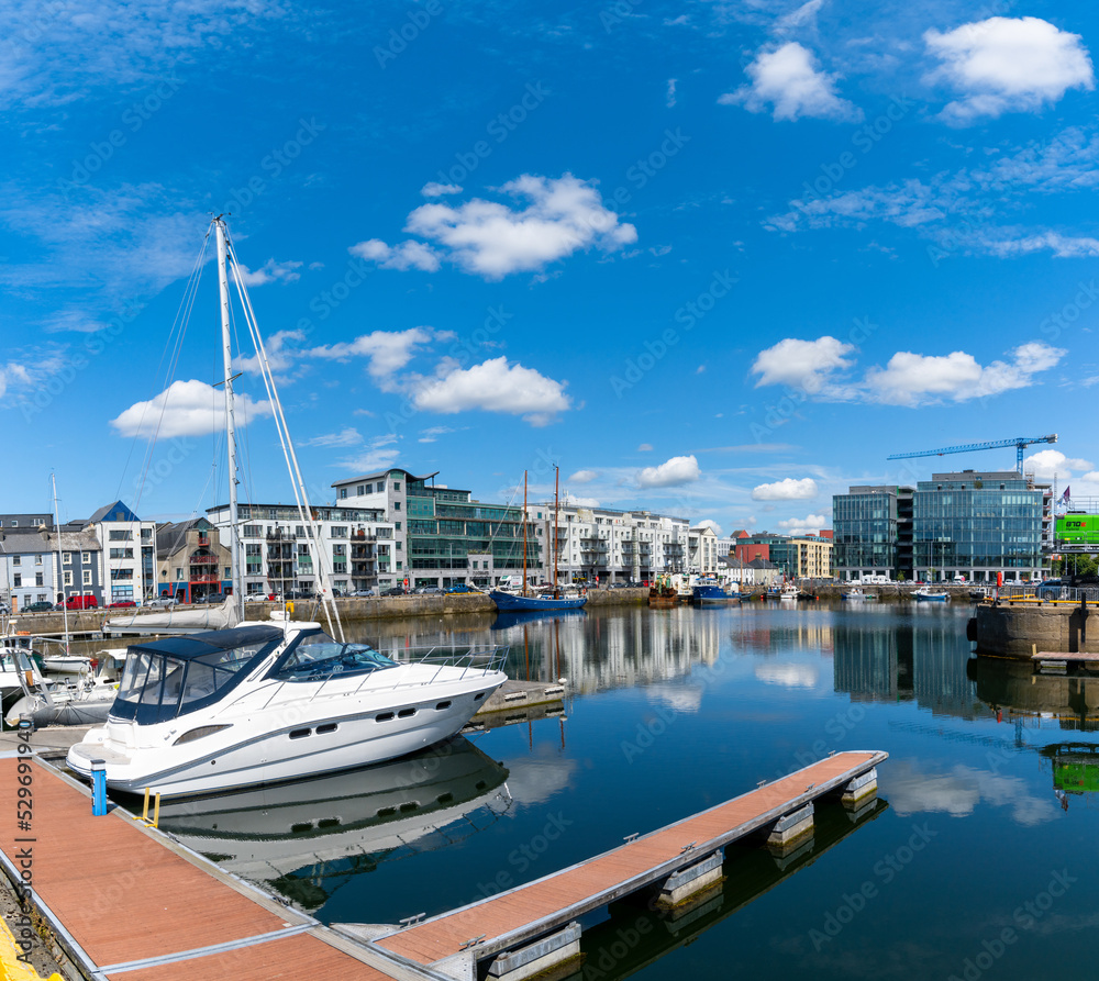view of the industrial port and sports marina in Galway with reflections in the calm water