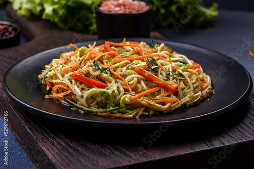 Fresh salad of sliced thin strips of carrot and zucchini on a concrete background