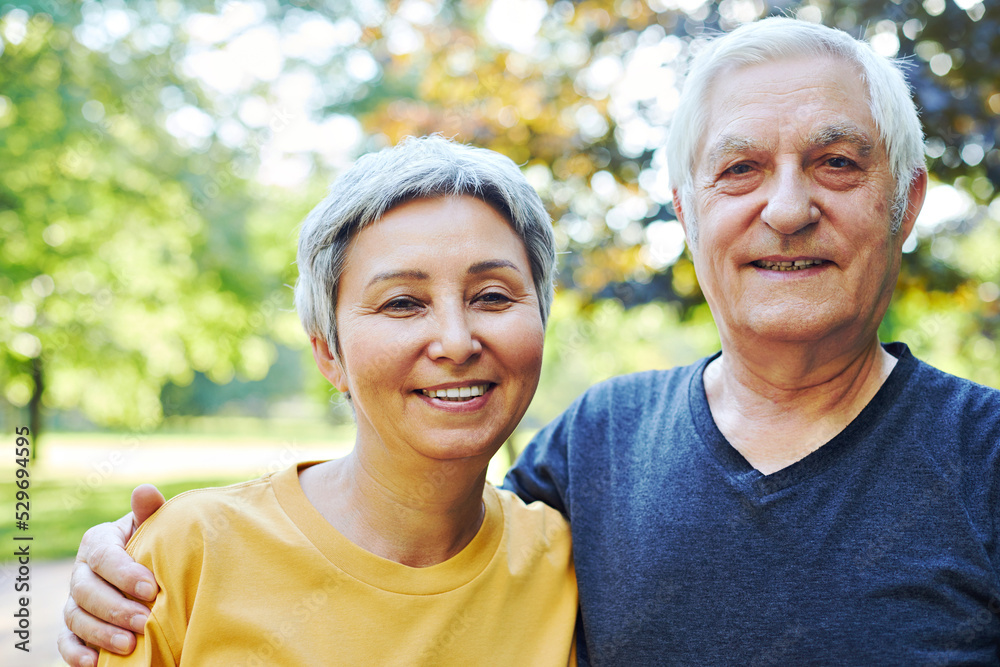 Portrait of attractive elderly 60s couple pose in park