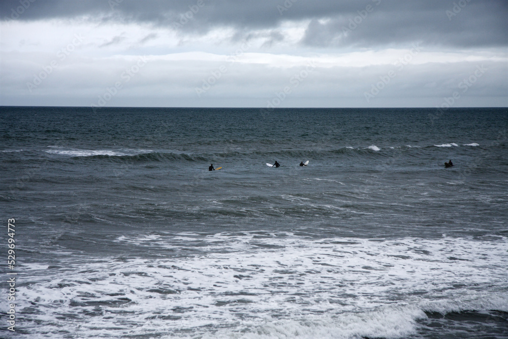 all weather surfers in sea at british seaside