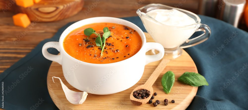 Pot of tasty pumpkin cream soup, spices and sauce on wooden background Pot of tasty pumpkin cream soup, spices and sauce on wooden background