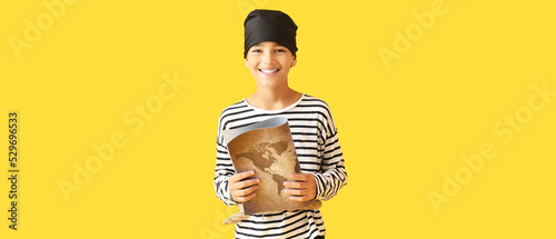Little boy dressed as pirate with treasure map on yellow background