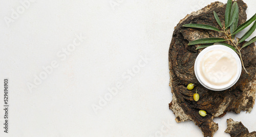 Jar of cream with olive oil extract and tree bark on white background with space for text, top view