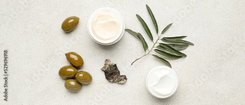 Jars of cream with olive oil extract on light background, top view