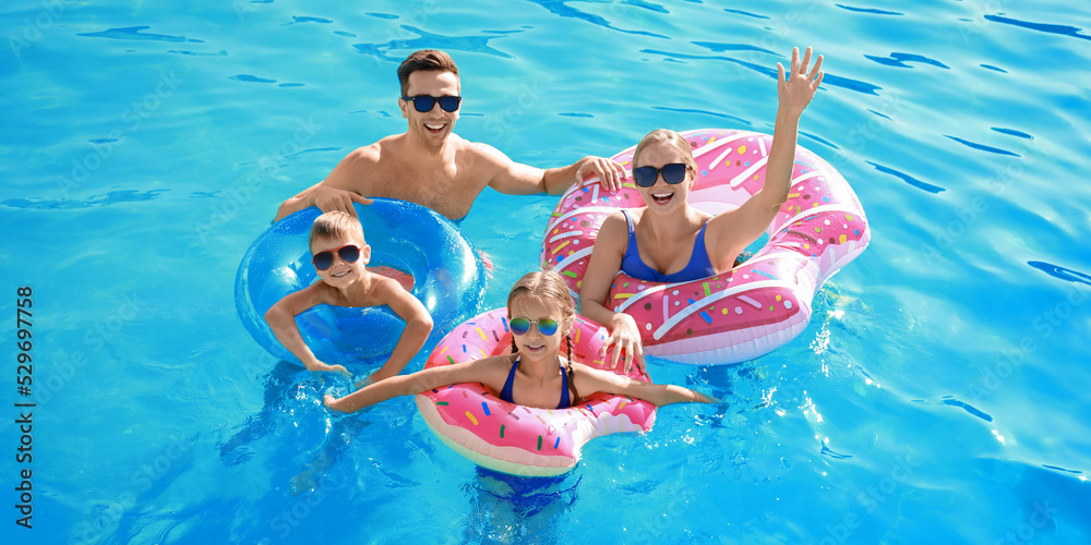 © Pixel-Shot - Happy family swimming in pool on summer day