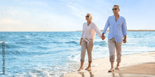 Canvastavla Happy mature couple walking on sea beach