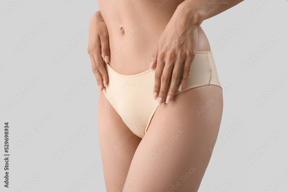 Slim young woman in underwear on light background - obrazy, fototapety, plakaty 