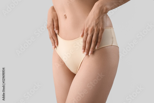 Slim young woman in underwear on light background