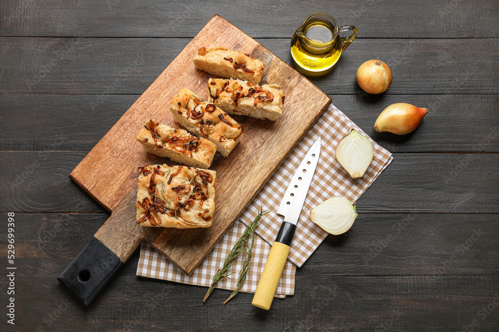 Composition with board of tasty Italian focaccia, onion and oil on dark wooden background