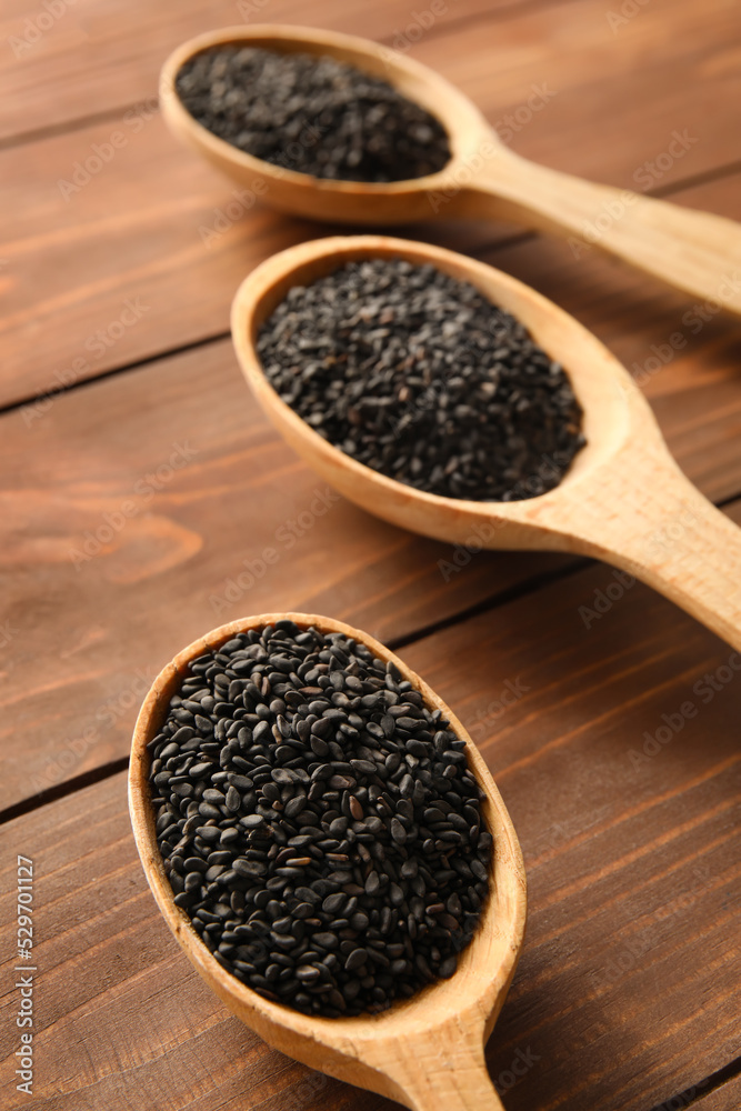 Spoons with sesame seeds on wooden background, closeup Spoons with sesame seeds on wooden background, closeup