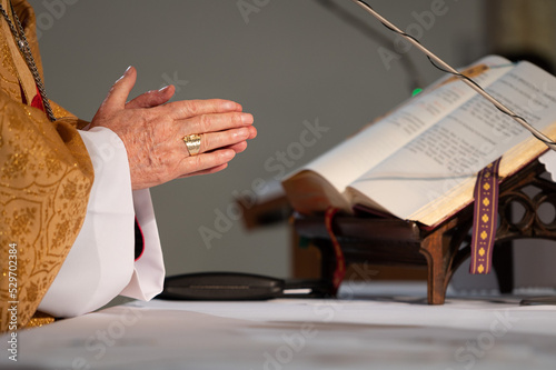 Fotografiet hands of the bishop with a ring on the finger in the background of the Bible