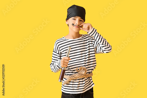 Little boy dressed as pirate with spyglass on yellow background