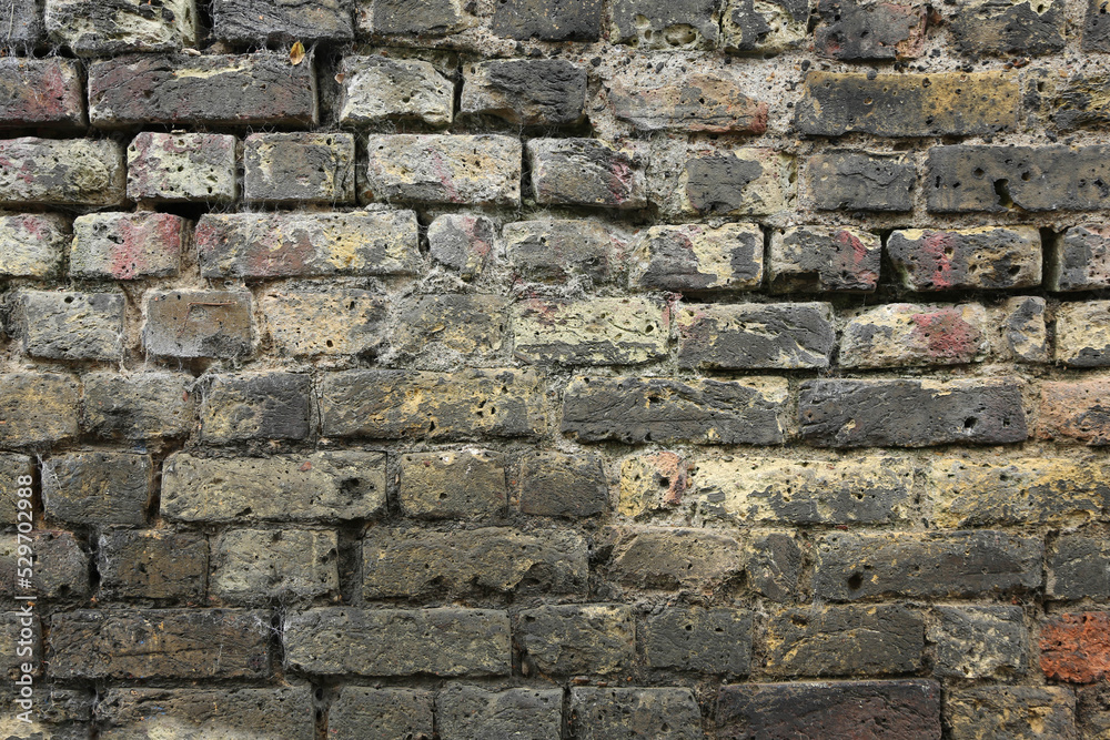An old brick wall with old dilapidated bricks of yellow and gray hue. The brick wall of a London street. London. An old brick wall with old dilapidated bricks of yellow and gray hue. The brick wall of a London street. London.