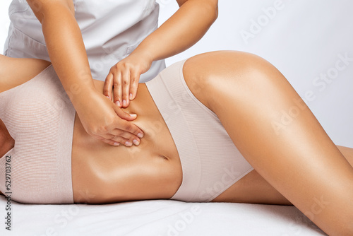 The masseur makes a massage on the abdomen, waist and hips in the spa. Overweight treatment, body sculpture. The concept of cosmetology and massage.