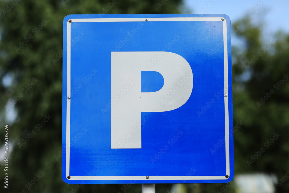 Closeup of a modern free parking sign road sign on nature park background. Isolated parking blue road sign with letter P on rectangular plate Closeup of a modern free parking sign road sign on nature park background. Isolated parking blue road sign with letter P on rectangular plate