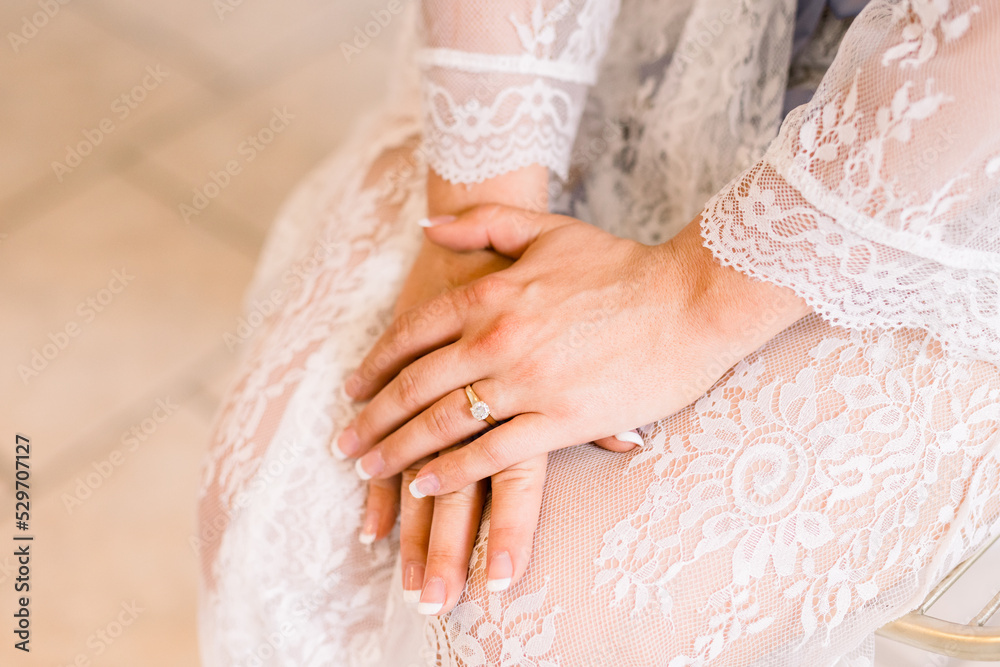 Bride is wearing a bridal robe with her hands held together Bride is wearing a bridal robe with her hands held together