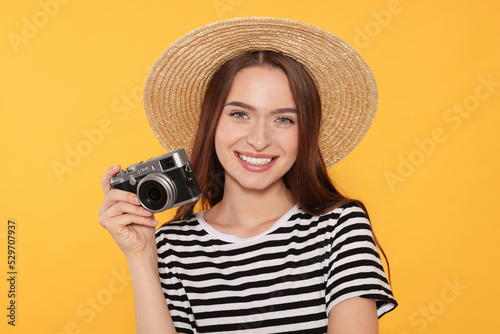 Young woman with camera on yellow background. Interesting hobby © New Africa