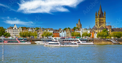Cologne, Germany - July 9. 2022: Beautiful panoramic rhine river skyline, St. Martin church, cruise ships, colorful medieval waterfront houses