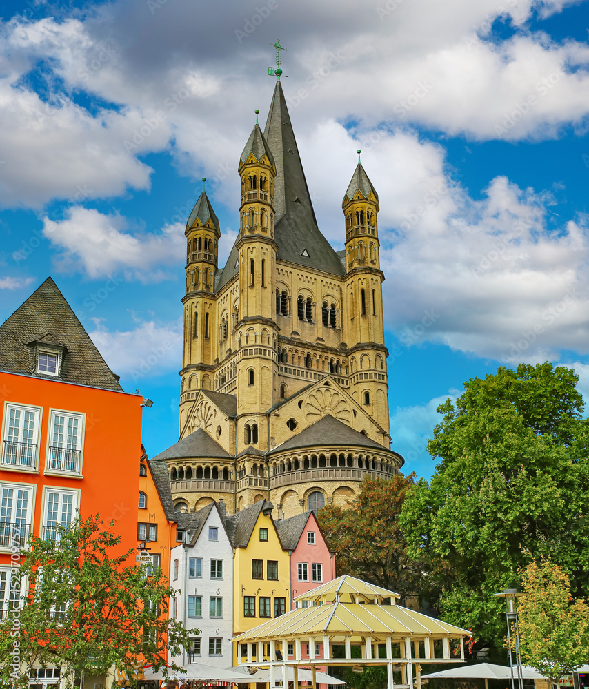 Cologne (Buttermarkt), Germany - July 9. 2022: Beautiful market square, colorful medieval old buildings, St. Martin church tower, cafe restaurants, blue summer sky
