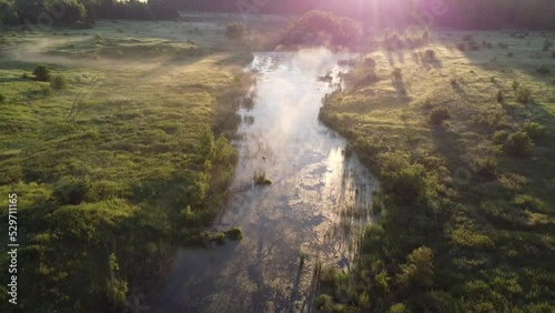 Aerial view on bog lake in foggy morning at sunrise aerial. Drone video.