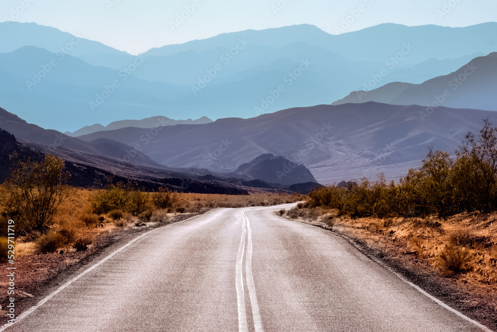 Fototapeta premium Lonely desert road winding away into distant mountains