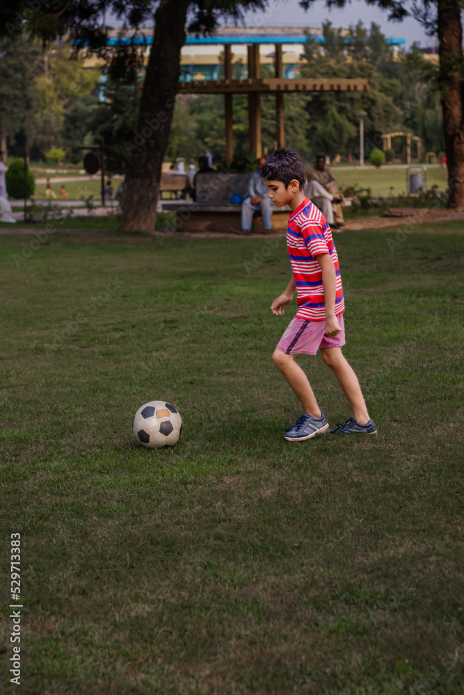 Obraz premium child playing football in a park
