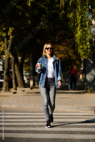 girl in a denim jacket with coffee in her hands crosses