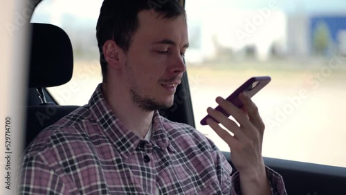 A passenger in a taxi is talking on the speakerphone on the phone or recording a voice message in the messenger