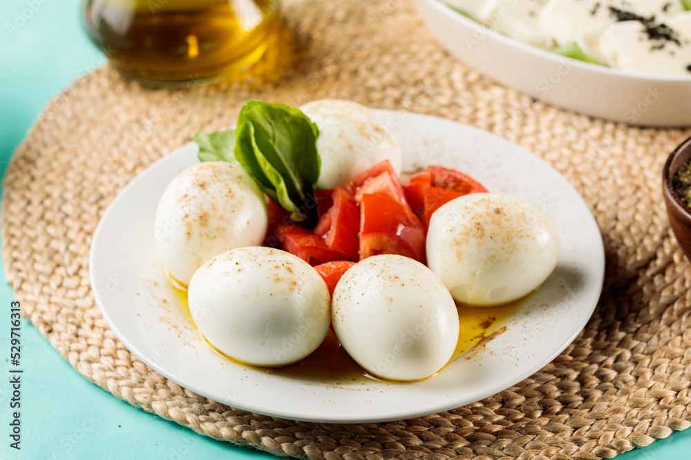 Boiled Eggs with tomatoes served in a dish isolated on cutting board side view Boiled Eggs with tomatoes served in a dish isolated on cutting board side view
