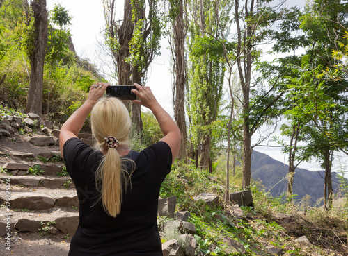 Blonde woman taking a picture in a forest.