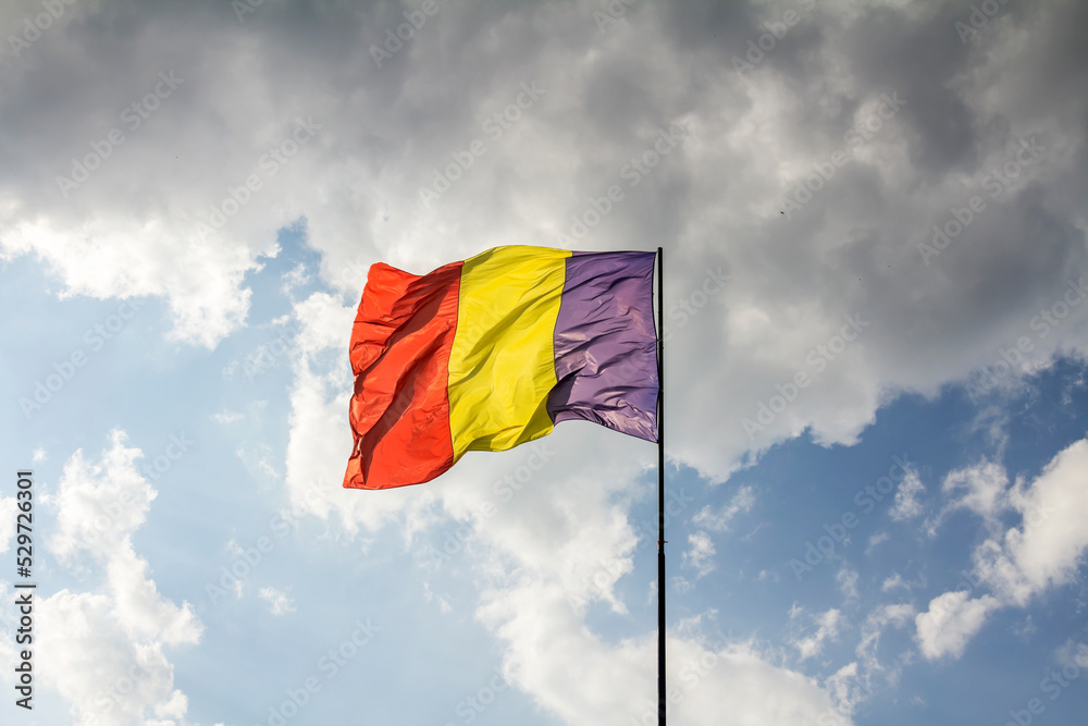 Romania flag on flagpole. waving in the wind on a blue sky with white cloudy Romania flag on flagpole. waving in the wind on a blue sky with white cloudy