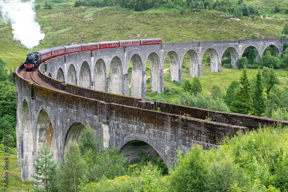 Jacobite locomotive train,blowing steam,crossing Glenfinnan Viaduct,amongst Scottish Highland scenery,Glenfinnan,Inverness-shire, Scotland.