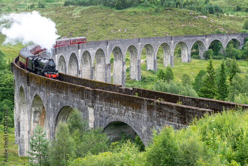 Jacobite locomotive train,blowing steam,crossing Glenfinnan Viaduct,amongst Scottish Highland scenery,Glenfinnan,Inverness-shire, Scotland.