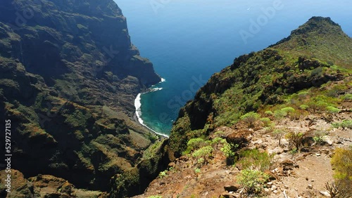 Flying over rocky canyon, huge cliffs, blue ocean shore. Reveal beautiful wide gorge Masca. Tenerife Island. Spain. Speactacular drone view of Atlantic coastline. photo