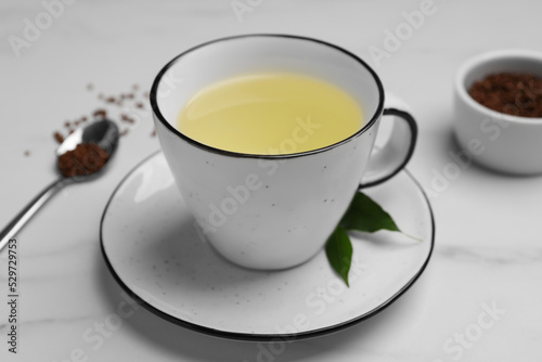 Cup of buckwheat tea on white marble table, closeup photo