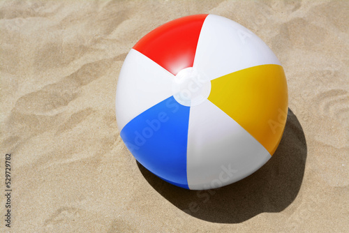 Colorful beach ball on sand, top view