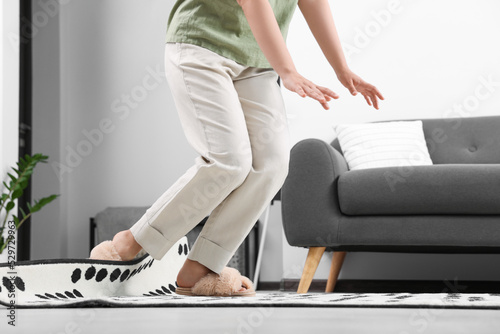 Woman tripping over carpet at home, closeup