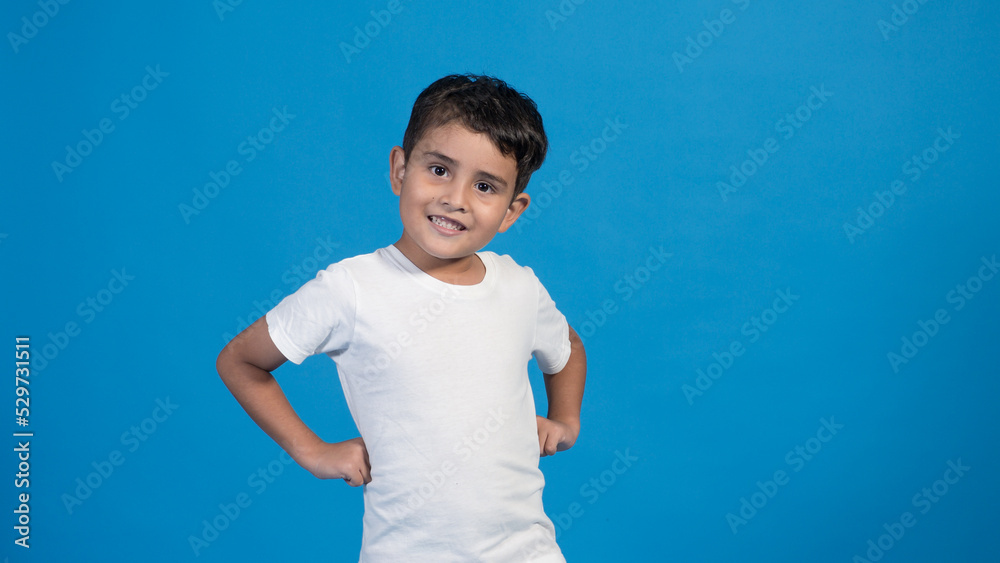 Hermoso niño con playera blanca y fondo azul con los posando para la cámara. Hermoso niño con playera blanca y fondo azul con los posando para la cámara.