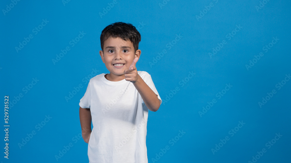 Hermoso niño con playera blanca y fondo azul. señalando con su dedo. Hermoso niño con playera blanca y fondo azul. señalando con su dedo.