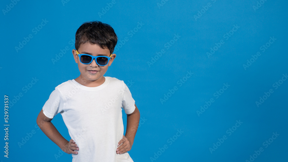 Hermoso niño con playera blanca y fondo azul. Posando para la cámara Hermoso niño con playera blanca y fondo azul. Posando para la cámara