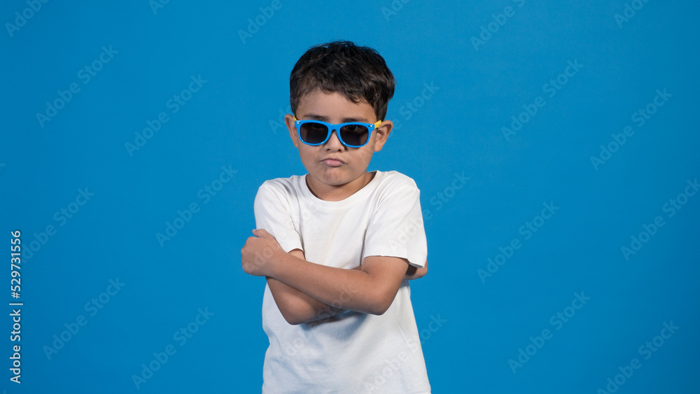 Hermoso niño con playera blanca y fondo azul. Usando lentes enojado Hermoso niño con playera blanca y fondo azul. Usando lentes enojado