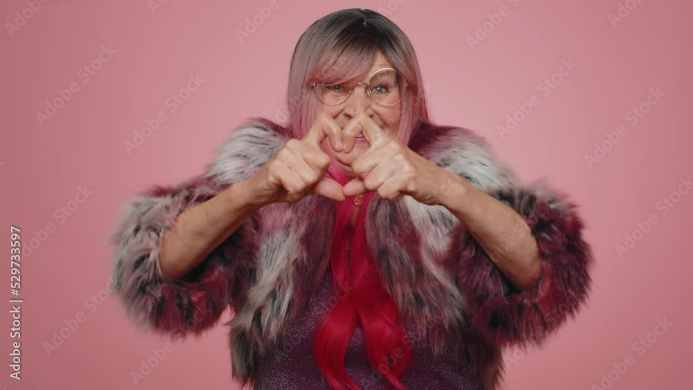 Woman in love. Smiling stylish old woman makes heart gesture demonstrates love sign expresses good feelings and sympathy. Senior elderly grandmother 70s isolated alone on pink studio wall background Woman in love. Smiling stylish old woman makes heart gesture demonstrates love sign expresses good feelings and sympathy. Senior elderly grandmother 70s isolated alone on pink studio wall background