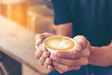 Close up hands of man sitting office desk holding sweet coffee cup relax and enjoy with happy time. Hot coffee mug in hand. Man holding coffee cup relaxing after work at office warm taste in cafe