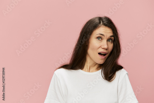 horizontal portrait of a cute, attractive, emotional woman on a pink background in a clean white t-shirt, with her mouth wide open