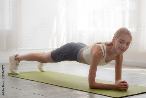 Young woman practice workout with posing plank on mat while motivation and determined at home, female doing weight training with strength and strong, one person, lifestyles and sport concept.